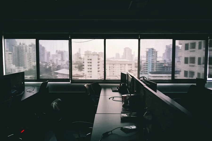 An empty corner office at dusk overlooking the city skyline