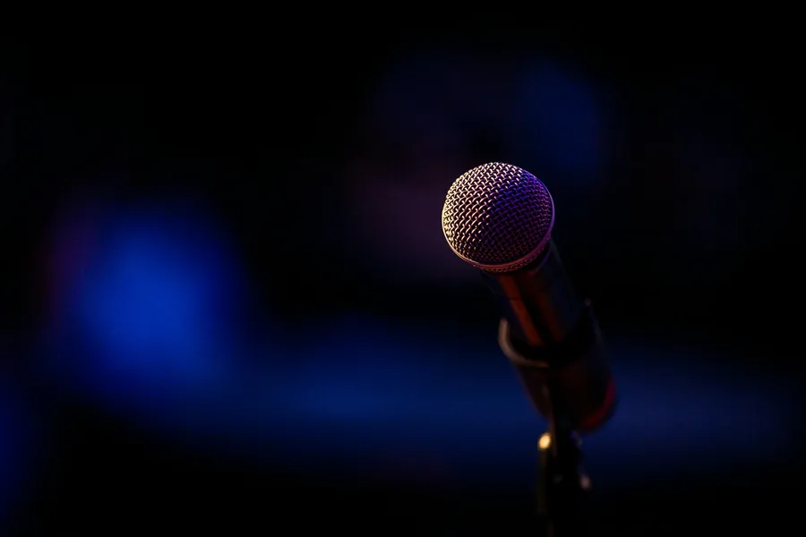 A single microphone lit in the dark, waiting at a podium
